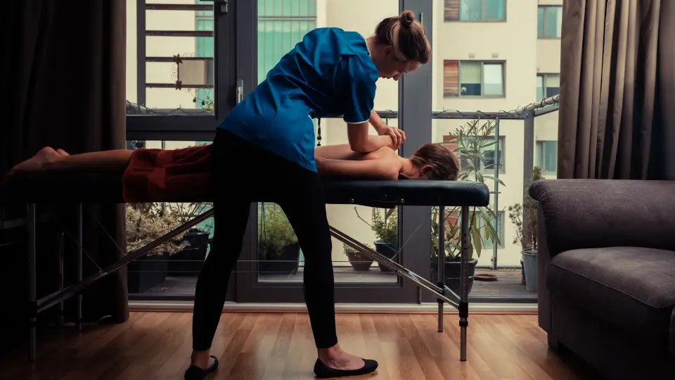 Massage therapist working with a client on a portable table in a home